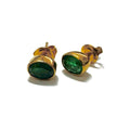 Gold earrings with green gemstones on a white background